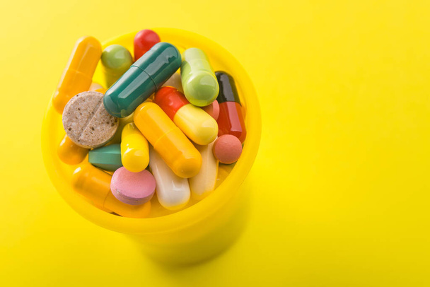 Montón de píldoras de cápsulas de color sobre un fondo amarillo. Brillante foto médica. - Foto, imagen