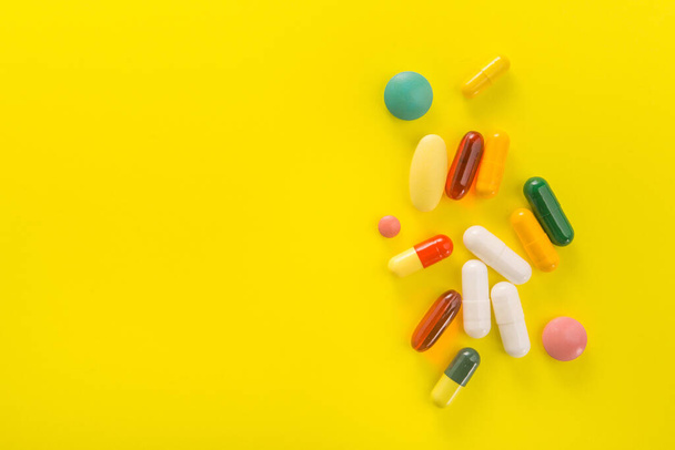 Pile de capsules colorées sur fond jaune. Brillante photo médicale. espace pour le texte. - Photo, image