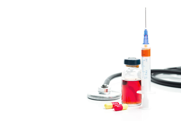 Stetoskop, ampule červené medicíny, injekční stříkačka a pilulky izolované na bílém pozadí. Léčba srdečních onemocnění. - Fotografie, Obrázek