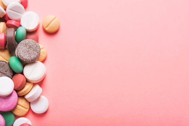 Pile of colored pills, capsule and tablets on a pastel pink background. - Photo, Image