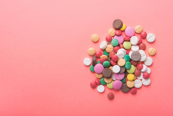 Stos kolorowych tabletek, kapsułek i tabletek na pastelowym różowym tle. Widok z góry. miejsce na tekst. - Zdjęcie, obraz