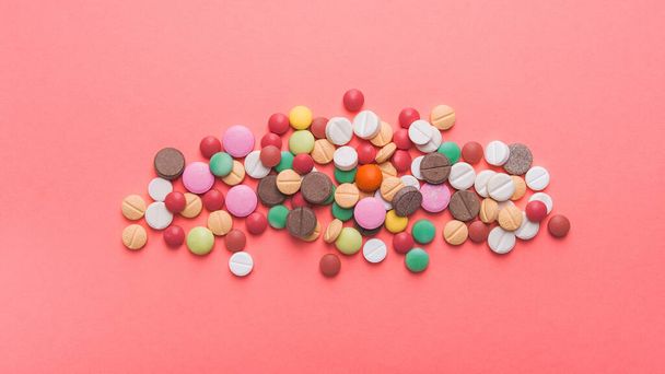 Montón de píldoras de colores, cápsulas y tabletas sobre un fondo rosa pastel. Vista superior. lugar para el texto. - Foto, imagen