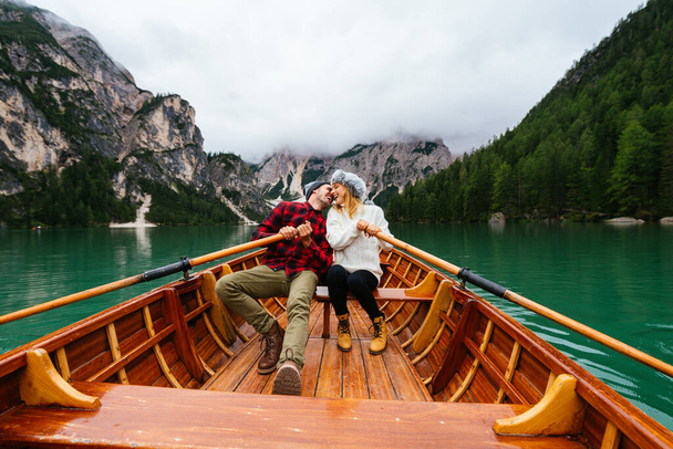 Beautiful couple of young adults visiting an alpine lake at Braies, Italy - Tourists with hiking outfit having fun on vacation during autumn foliage - Concepts about travel, lifestyle and wanderlust - Photo, image