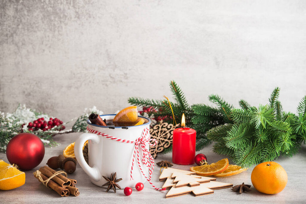 Glühwein mit Gewürzen und Weihnachtsdekoration auf weißem Steingrund. Neujahrsferien-Konzept. - Foto, Bild