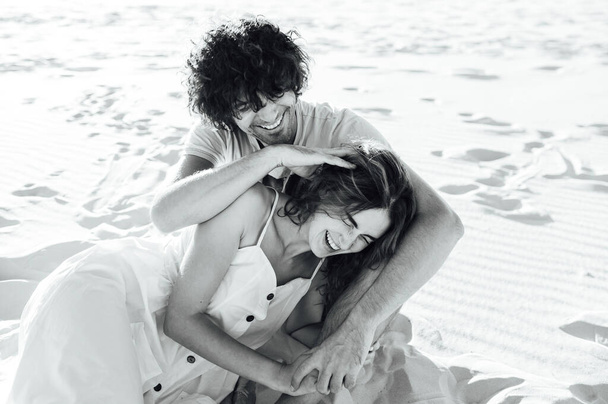 A curly-haired guy and a beautiful girl are having fun on the beach - Foto, Imagen