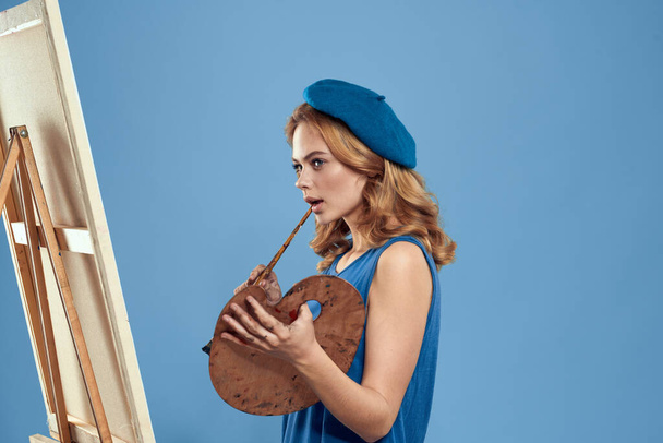 Woman artist blue beret drawing palette easel hobby creativity blue background - Photo, Image