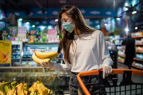 The girl with surgical mask is going to buy bananas. - Photo, Image