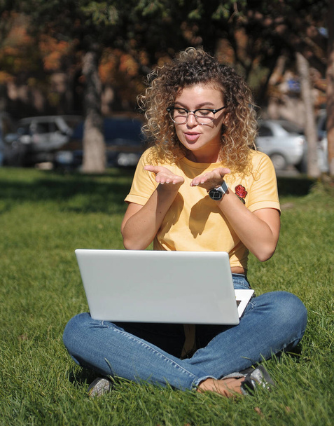 Молода жінка з ноутбуком на відкритому повітрі. Онлайн-освіта, Студент на дистанційній освіті працює з ноутбуком
. - Фото, зображення