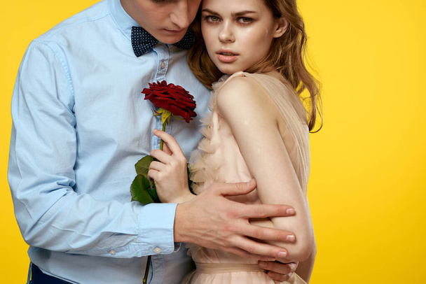 Enamored man and woman with red rose on yellow background cropped view close-up romance - Foto, afbeelding