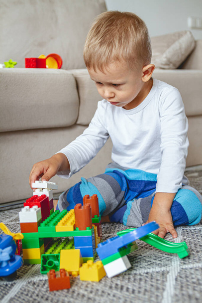 Child playing with toy blocks sitting on the floor - Foto, Imagem