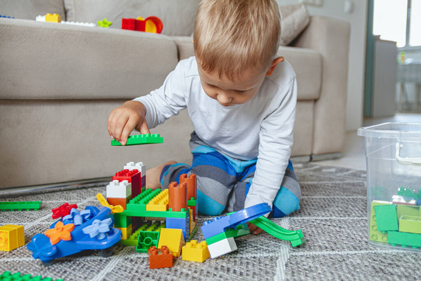 Child playing with toy blocks sitting on the floor - 写真・画像