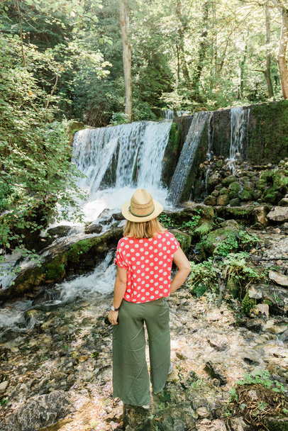 Young female nature explorer standing in front of the waterfall - Fotoğraf, Görsel