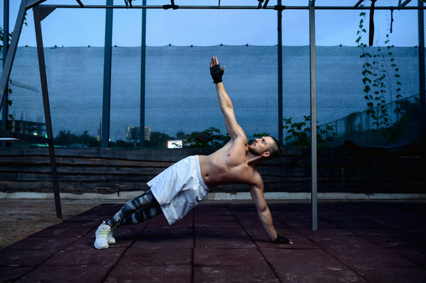 Vahva mies treenaa, treenaa kadulla. Kuntoilukoulutus urheilukentällä ulkona, miespumput lihaksia, aktiivinen urbaani elämäntapa - Valokuva, kuva