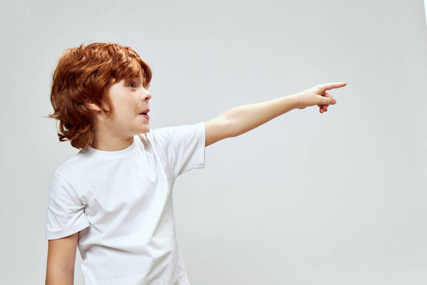 感情的な赤髪の少年は、サイドビューに指を示しています  - 写真・画像