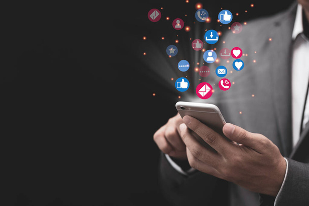 Social Media und Marketingkonzept: Geschäftsmann hält weißes Smartphone in der Hand und nutzt bunte Social-Media-Symbole. - Foto, Bild