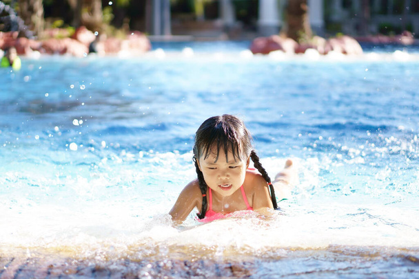 Crianças asiáticas bonito ou criança menina usar biquíni rosa para nadar ou respingo de água brincando e sorrir com diversão feliz na piscina ou parque aquático para refrescar e relaxar com exercício nas férias de verão - Foto, Imagem