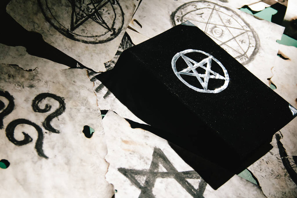 Оккультный гримуар, магическая книга, лежащая на столе с оккультными символами, свечами, пентаграммами, предсказаниями судьбы, ритуалами, алтарем, спиритизмом, секретными знаниями, черепом - Фото, изображение