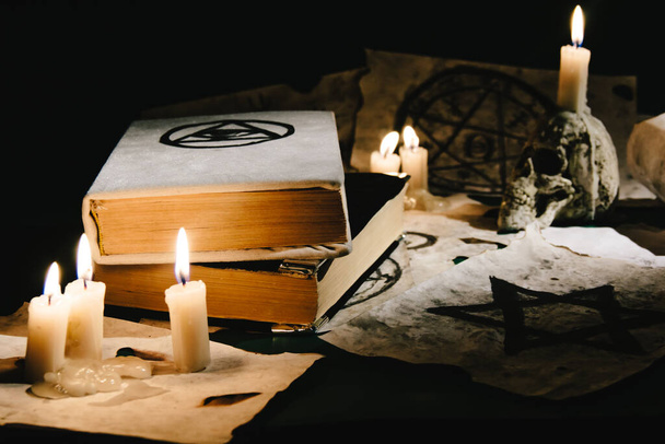Occult grimoire, magic book laying on table with occult symbols, candles, pentagrams, fortune telling, ritual, altar, spiritism, secret knowledge, scull - Photo, Image