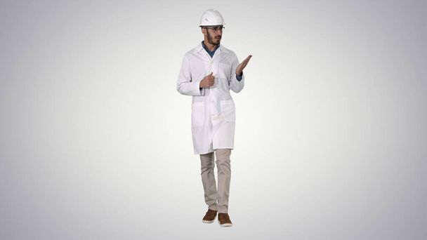Scientist in white robe and helmet presenting pointing to side w - Φωτογραφία, εικόνα