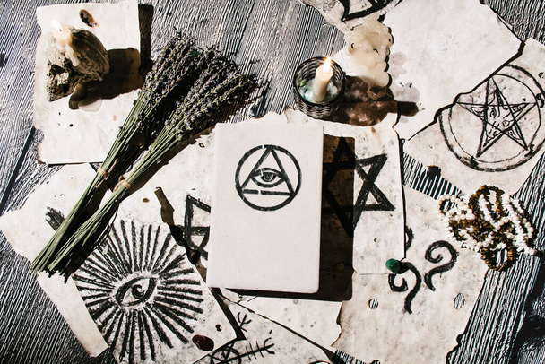 White magic book laying on the table with old manuscripts with occult symbols, candles, lavender. Concept of fortune telling, ritual, altar, spiritism, secret knowledge - Φωτογραφία, εικόνα