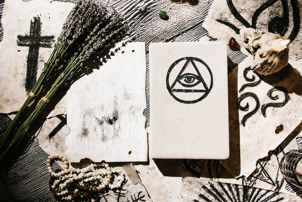 White magic book laying on the table with old manuscripts with occult symbols, candles, lavender. Concept of fortune telling, ritual, altar, spiritism, secret knowledge - Photo, Image