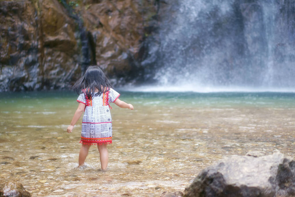 Ázsiai gyerekek aranyos vagy viszont gyerek lány és a hegy törzs szórakoztató és élvezze a játék víz splash vízesés vagy folyó és nyaralás pihenni kirándulás nyáron Jokkradin vízesés térrel - Fotó, kép