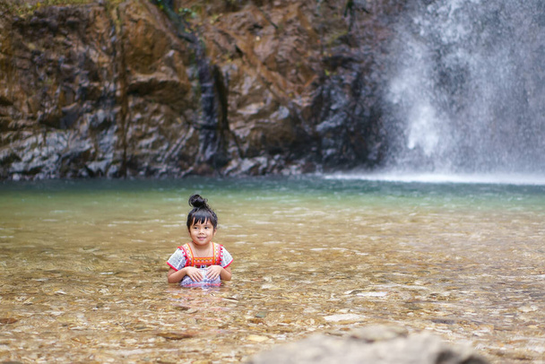 アジアの子供たちはかわいいまたは子供の女の子と丘の部族は楽しく笑顔で、滝や川で水のスプラッシュを楽しんで、夏の休暇は宇宙とジョククラディンの滝でリラックス旅行 - 写真・画像