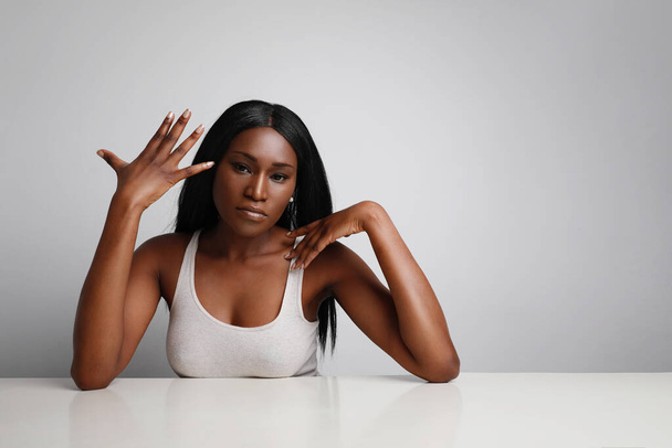 Retrato da jovem negra, com pele perfeita. Posando sobre fundo branco e mostrando uma mão. Espaço para texto.  - Foto, Imagem