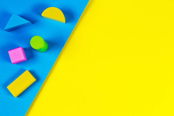 Bloques coloridos de madera sobre fondo geométrico amarillo y azul. Vista superior, plano - Foto, imagen