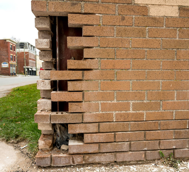 Bricks missing from the corner of a brick wall. An I beam is behind the wall.  - Photo, Image