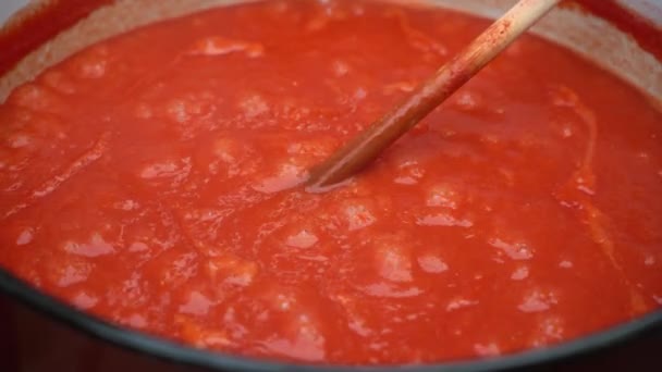 Primer plano en olla grande con cuchara de madera revolviendo ketchup caliente o salsa de tomate o sopa mientras se cocina al aire libre - hecho en casa con la receta tradicional concepto de alimentos orgánicos - Imágenes, Vídeo