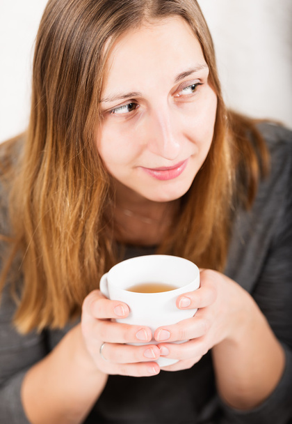 Happy girl in grey holding mug and not looking at camera - 写真・画像