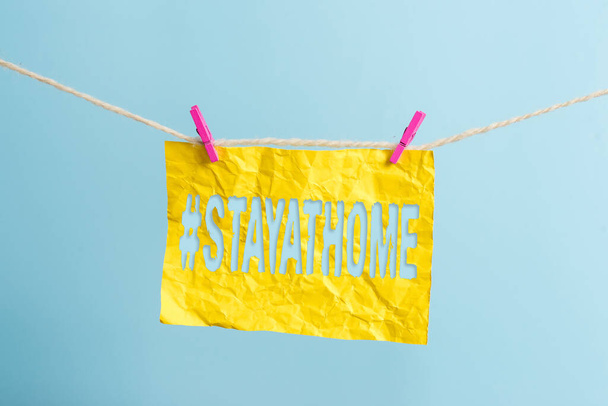 Word writing text Hashtag Stay at home. Business concept for a trending label in social media related to the coronvirus outbreak Clothesline clothespin rectangle shaped paper reminder white wood desk. - Photo, Image
