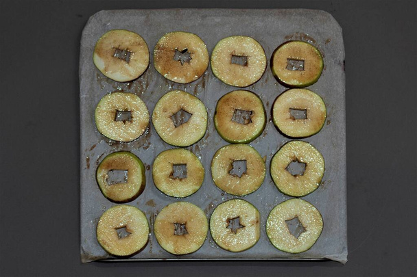 Frisch gepflückte Äpfel entkernen, in dünne Apfelringe schneiden, mit Kokosöl und Zimt bestreichen und im Ofen 90 Minuten backen. Lassen Sie sie trocknen. - Foto, Bild
