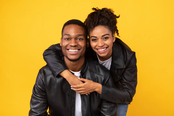 Любимая афроамериканская пара обнимается в студии на желтом фоне - Фото, изображение
