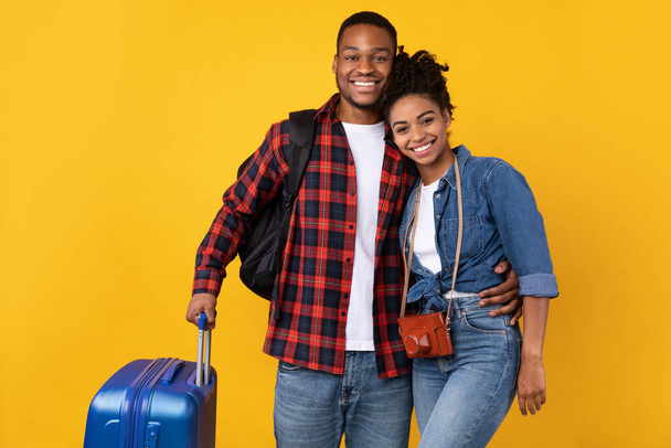 Afroamerikanisches Paar posiert mit Gepäck auf gelbem Hintergrund - Foto, Bild