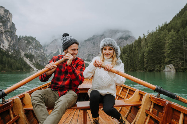 Beautiful couple of young adults visiting an alpine lake at Braies, Italy - Tourists with hiking outfit having fun on vacation during autumn foliage - Concepts about travel, lifestyle and wanderlust - Zdjęcie, obraz