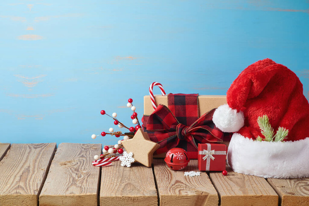Christmas holiday background with Santa hat, gift boxes and decorations on wooden table - Foto, Imagem