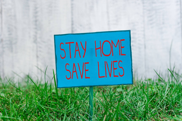 家庭を救う生活を示す概念的な手書き。家を出ないことによる感染患者数の減少を示す事業写真芝生の棒に取り付けられ配置された平板紙 - 写真・画像