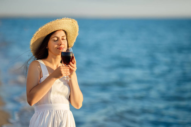 mulher segurando copo de vinho junto ao mar - Foto, Imagem