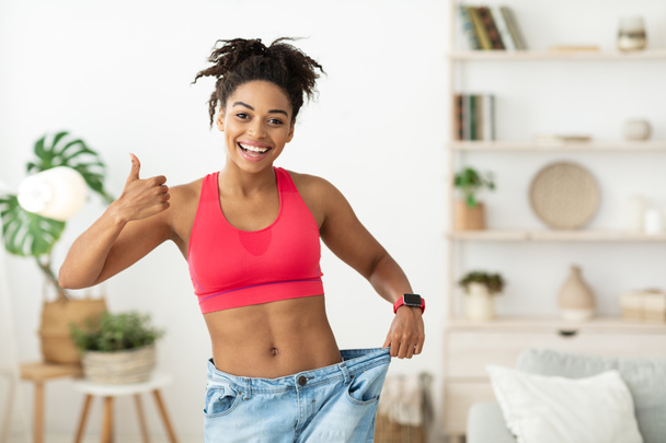 Slim African American Lady Gesturing Thumbs-Up Aprovando Dieta em pé dentro de casa - Foto, Imagem