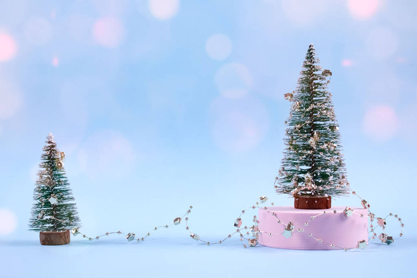 Christmas trees or New Year trees with Christmas decorations and pink bokeh lights on trendy blue background with copyspace for text or presentation. Selective focus, place for text - Photo, Image