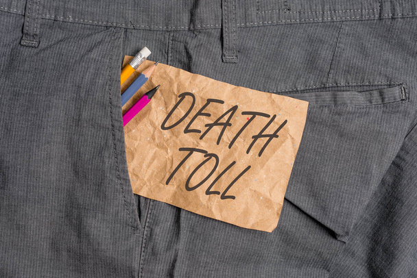 Текст слова Death Toll. Бизнес-концепция для количества смертей в результате конкретного инцидента Письменное оборудование и коричневая бумага для банкнот внутри кармана рабочих штанов человека. - Фото, изображение