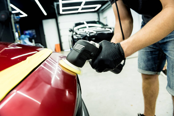 Car service worker polishes a car details with orbital polisher. - Foto, Imagem
