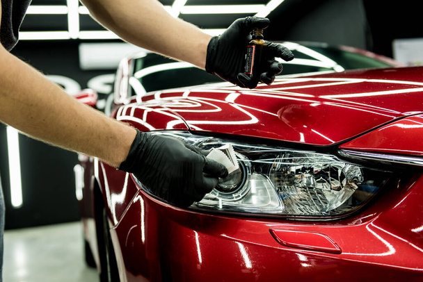 Car service worker applying nano coating on a car detail. - Фото, зображення