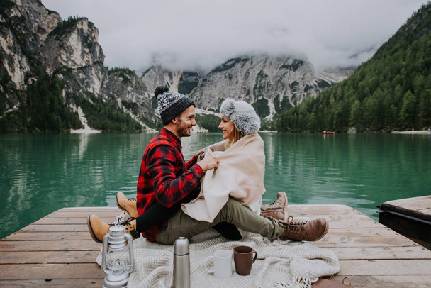 Beautiful couple of young adults visiting an alpine lake at Braies, Italy - Tourists with hiking outfit having fun on vacation during autumn foliage - Concepts about travel, lifestyle and wanderlust - Φωτογραφία, εικόνα