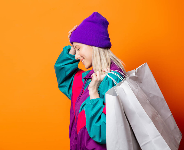 Style woman in 90s tracksuit with shopping bags on orange background - Foto, Bild