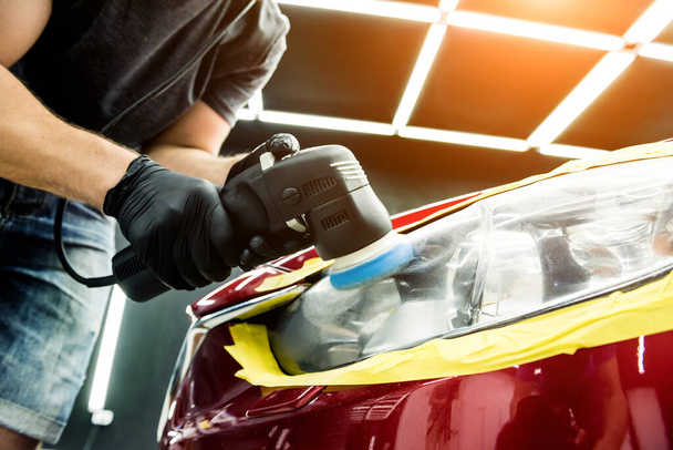 Car service worker polishes a car details with orbital polisher. - Фото, изображение