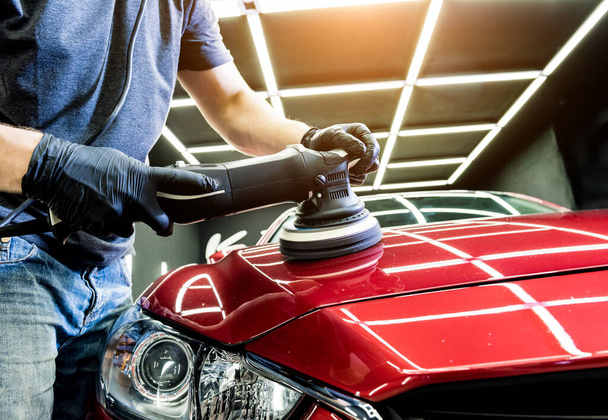Car service worker polishes a car details with orbital polisher. - Foto, afbeelding