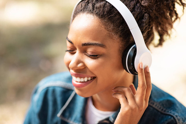 Schwarze Dame im Kopfhörer hört Musik mit geschlossenen Augen - Foto, Bild